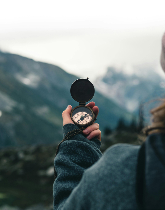 Explorer holding compass outdoors, embodying Trail Ridge Power's focus on vision and direction